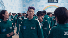 a group of people are standing in a room and one of them has the number 230 on his jacket