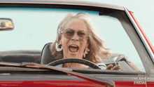 a woman is driving a red car with the words freakier friday written on the side