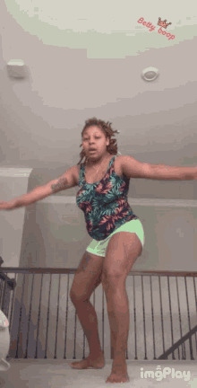 a woman in a tank top and shorts is dancing with a betty boop sticker on the ceiling above her