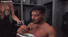 a shirtless wrestler is being interviewed by a woman in a locker room with the hashtag #thekamdreesen