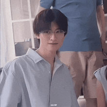 a man wearing glasses and a light blue shirt has a aa + gif watermark