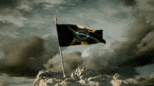 a flag on top of a mountain with a cloudy sky behind it