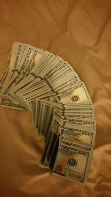 a bunch of hundred dollar bills are stacked on top of each other