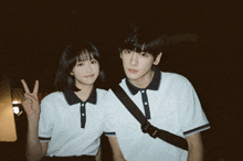 a boy and a girl are standing next to each other and the girl is giving a peace sign
