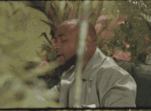 a man with a beard and earrings is sitting in front of some flowers