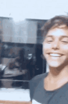 a young man is smiling in a kitchen while standing in front of a refrigerator .