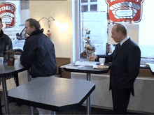 a man in a suit stands in front of a sign that says ' hamburger '