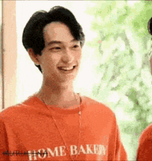 a man wearing a red t-shirt that says home bakery is smiling .