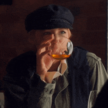 a woman in a hat is drinking a glass of whiskey