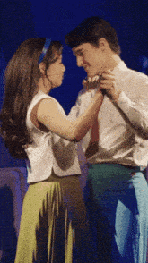 a man and a woman are dancing in front of a blue backdrop