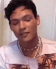 a man wearing a pearl necklace and earrings is making a face .