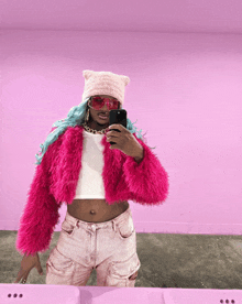 a woman in a pink fur coat taking a selfie