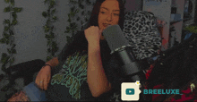a woman sitting in front of a microphone with breeluxe written in the corner
