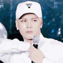 a man wearing a white hat and holding a microphone .
