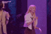 a woman is singing into a microphone while standing next to another woman on a stage .