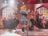 a group of men are dancing on a stage with a clown in a costume .