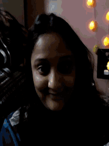 a close up of a woman 's face with candles on the wall behind her
