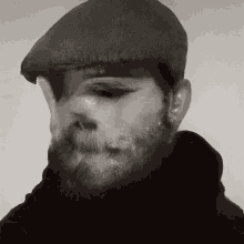 a man with a beard wearing a hat and a black shirt