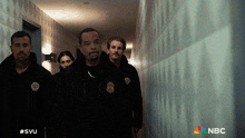 a group of police officers walking down a hallway with the nbc logo in the corner