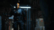 a man in a superhero costume is standing in a dark room with a sword in his hand .
