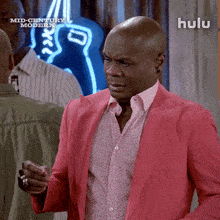 a man in a pink suit is standing in front of a neon sign that says mid century modern