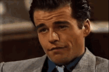 a close up of a man 's face with a suit and tie