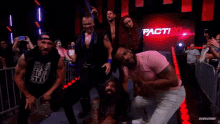 a group of wrestlers are posing for a picture in front of a crowd at a wrestling event .