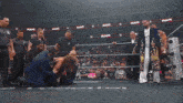 a man is laying on the ground in a wrestling ring while a referee stands behind him .