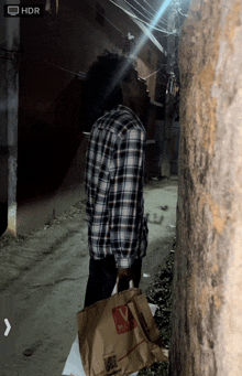 a man in a plaid shirt is holding a bag that says max on it
