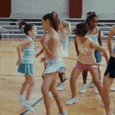 a group of young girls are dancing in a gym and one girl has the number 32 on her shirt