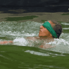 a woman wearing a green headband is swimming in a body of water