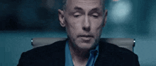 a man in a suit and blue shirt is sitting in an office chair .