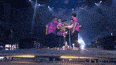 a group of people standing on a stage with one wearing a purple shirt that says ' nirvana ' on it