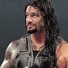 a man with long hair and a beard is wearing a vest and looking at the camera .