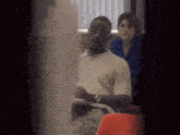 a man wearing glasses sits in a classroom with other people