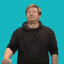 a man in a black hoodie holds his fist up in front of a blue background