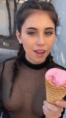 a woman is holding a pink ice cream cone