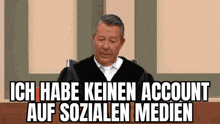 a man is sitting at a table with a sign that says `` ich habe keinen account auf sozialen medien ''