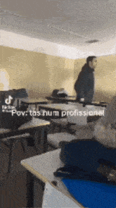 a man is standing in a classroom with tables and chairs and a caption that says pov : tas num profissional .