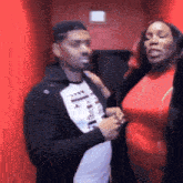 a woman in a red dress is standing next to a man in a black jacket ..