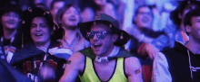 a group of people are sitting in a stadium and one of them is wearing a hat and sunglasses .