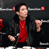 a man sitting at a table with a spoon in his hand and a sign that says bonchon