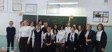 a group of children are posing for a picture in front of a blackboard that has hearts on it