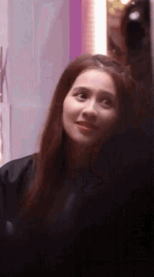 a woman with long dark hair is looking at herself in the mirror