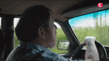 a man is driving a car with a c on the bottom right