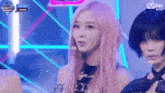 a girl with pink hair is standing on a stage with a microphone .