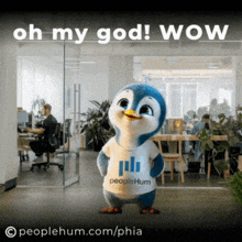 a stuffed penguin wearing a peoplehum shirt stands in an office