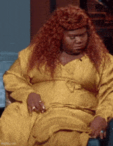 a woman with red hair and a yellow dress is sitting in a chair .