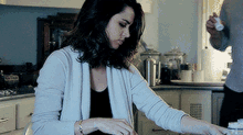 a woman is sitting at a table in a kitchen