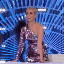 a woman in a pink sequined dress is sitting on a stage .